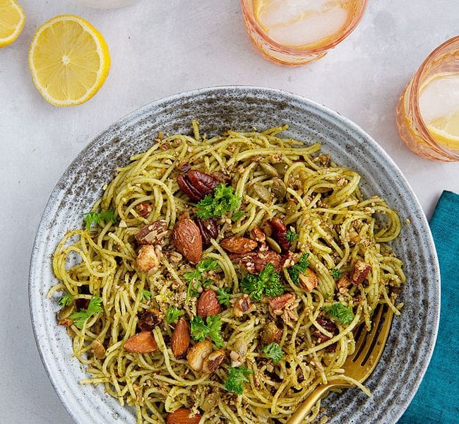 Bowl of pasta topped with herbs and nuts